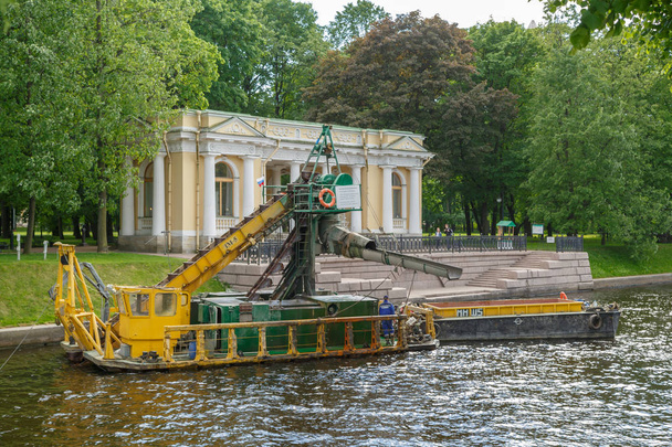 SAINT-PETERSBURG, RUSSIA, MAY 30, 2018: Small river non self-propelled multi-bucket dredger with a barge cleans the river Moika - Photo, Image