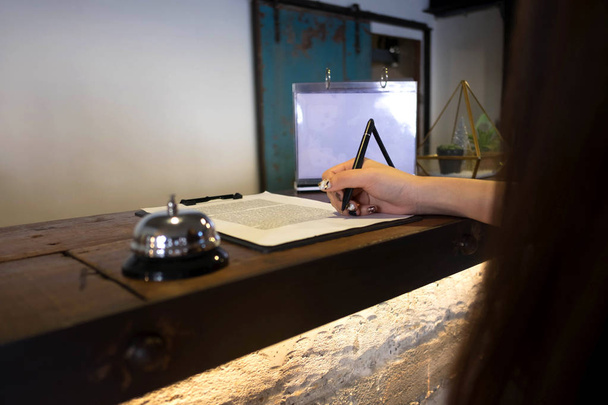 Nahaufnahme von Frauen beim Unterschreiben und Ausfüllen von Formularen an der Hotelrezeption. - Foto, Bild