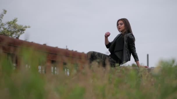 A menina jovem em uma jaqueta preta senta-se na pedra. Ela olha para a distância
. - Filmagem, Vídeo