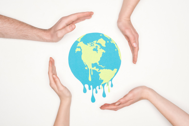 paper cut melting earth surrounded by male and female hands on white background, global warming concept - 写真・画像