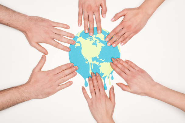 частичное представление о женщинах и мужчинах, кладущих руки на бумагу, разрезающую земной шар на белом фоне, концепция глобального потепления
 - Фото, изображение