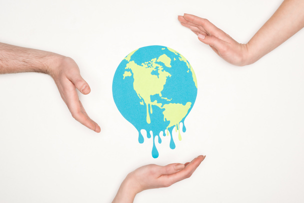 cropped view of male and female hands around paper cut melting globe on white background, global warming concept - 写真・画像