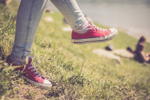 Black sneakers and green grass in the summer: free time for teenager - Фото, зображення