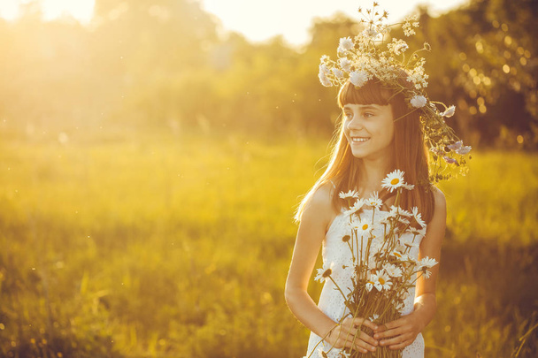 Menina feliz em um prado do por do sol com um buquê de camomilas floridas
 - Foto, Imagem