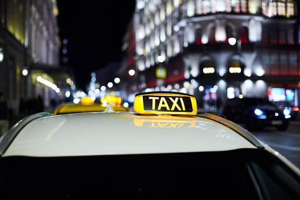 Het grote taxi teken op de achtergrond van de nacht stad - Foto, afbeelding