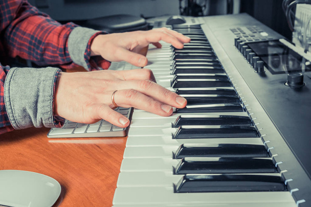 Чоловічий музикант, який грає синтезатор клавіатури Midi у студії звукозапису, зосереджується на руках. Чоловічі герби грають сольну музику або нову мелодію. Крупним планом
 - Фото, зображення