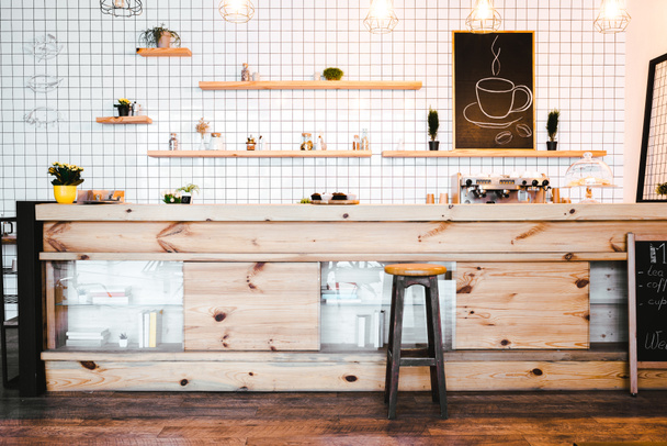 wooden brown bar counter with plants and cupcakes, drawing on shelf in coffee house - Fotoğraf, Görsel