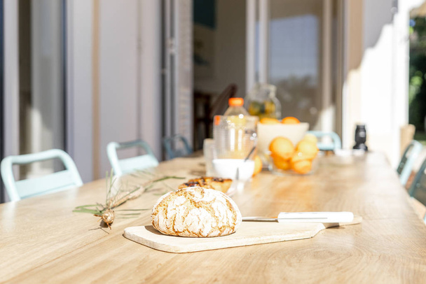 Хлеб на деревянной доске с ножом на столе снаружи дома
 - Фото, изображение