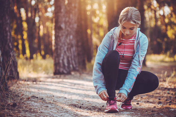 woman Runner tying shoelaces on sneakers. Morning jogging in the forest. Fitness - Fotoğraf, Görsel