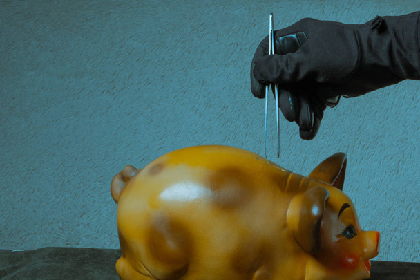 Ληστεία τράπεζας. Έννοια μαύρο φορημένο γάντια χέρι παίρνει χρήματα από την τράπεζα γουρουνάκι - Φωτογραφία, εικόνα