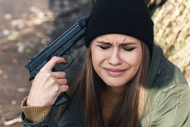 Młoda kobieta z pistoletu ma zamiar popełnić samobójstwo na zewnątrz - Zdjęcie, obraz