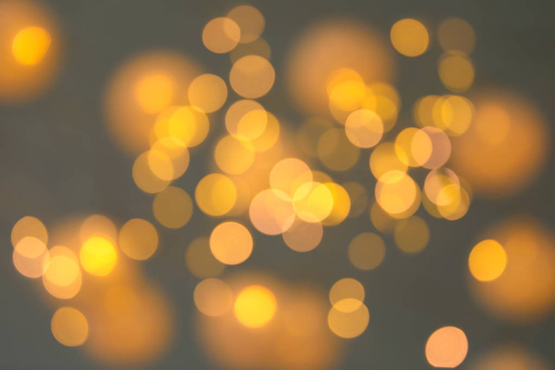 Blurred view of gold lights on dark background. Bokeh effect - 写真・画像