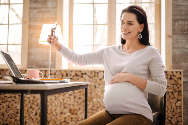 Happy pregnant woman taking selfie - 写真・画像