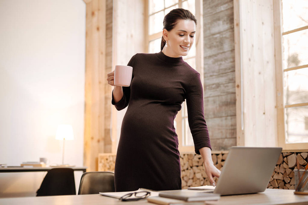 Thoughtful pregnant businesswoman taking tea - 写真・画像