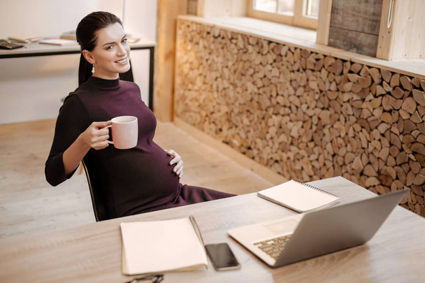 Satisfied pregnant businesswoman sipping tea - Photo, image