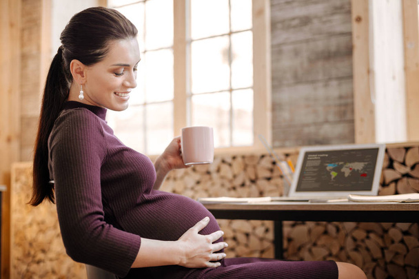 Adorable pregnant businesswoman caressing her tummy - Foto, Bild