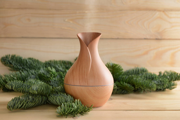 Aroma oil diffuser and coniferous branches on wooden table - Photo, Image