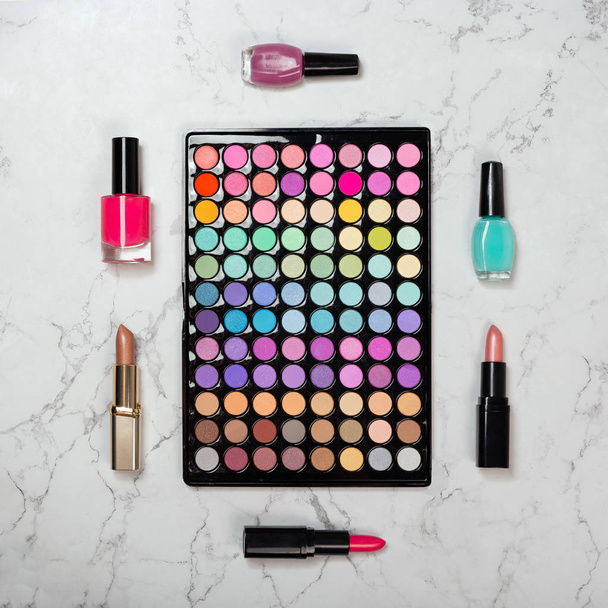 Flat lay of makeup eyeshadow palette with decorative cosmetics on marble texture - Photo, image