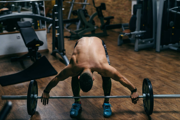 Νέοι ισχυρή Καυκάσιος shirtless bodybuilder άρση της barbell. Εσωτερικό γυμναστήριο. - Φωτογραφία, εικόνα