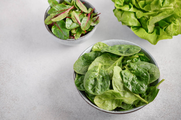 frische grüne Salatblätter in einer Schüssel auf grauem Betongrund, selektiver Fokus. - Foto, Bild