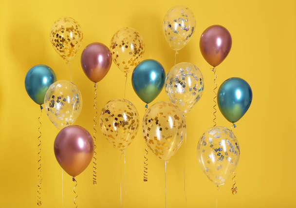 Bright balloons with ribbons on color background - Foto, Imagem