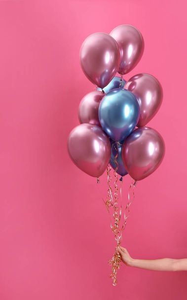 Woman holding bunch of balloons on color background, closeup - Фото, зображення