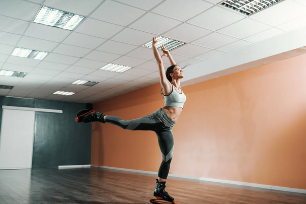 Belle coupe brune caucasienne en sportswear sautant sur kangoo saute des chaussures dans la salle de gym
. - Photo, image