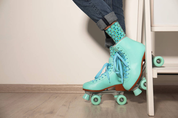 Young woman with retro roller skates against light wall, closeup. Space for text - Fotografie, Obrázek