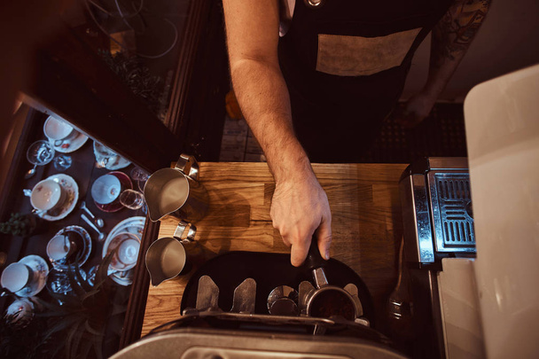 Top view of the barista hand which inserts a portafilter with ground coffee into the coffee machine - 写真・画像