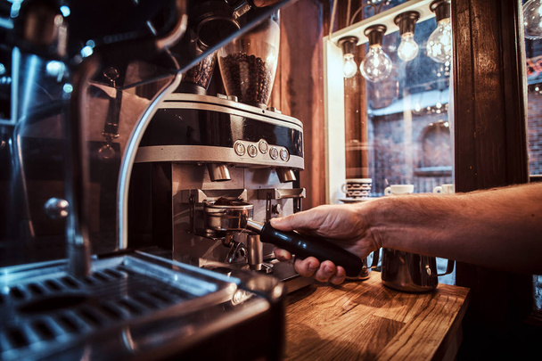 Barista houden een portafilter met een zwarte gemalen koffie in een café, winkel of restaurant - Foto, afbeelding