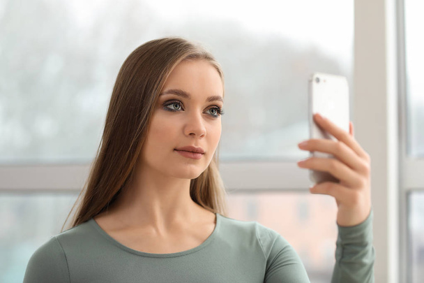 νεαρή γυναίκα που παίρνει selfie με κινητό τηλέφωνο στο σπίτι - Φωτογραφία, εικόνα
