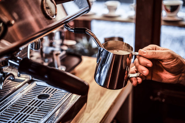 Barista working on steam espresso coffee machine in a coffee shop - 写真・画像