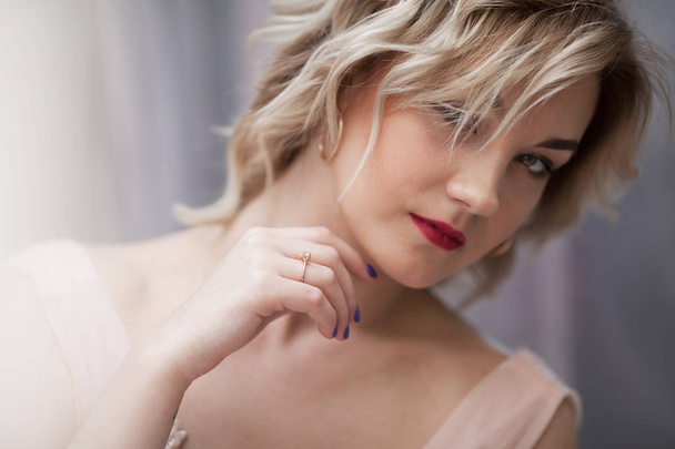 Beautiful blonde model girl with short curly hair. Red lips. Fashion, beauty and emotional portrait. - Фото, изображение