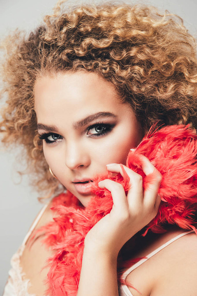 Close view portrait of young curly woman with stylish makeup and feathers in hands - Valokuva, kuva