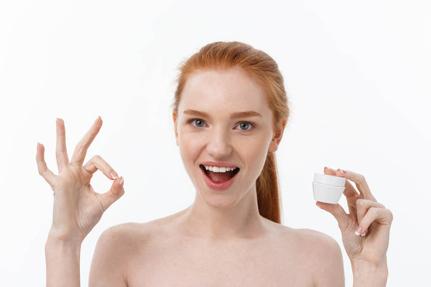 portrait of beautiful woman smiling while taking some facial cream isolated on white background with copy space. - 写真・画像