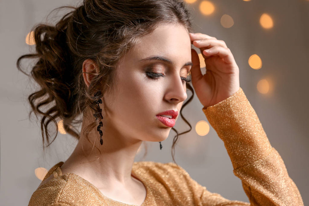 Mujer joven con hermosas joyas contra luces desenfocadas
 - Foto, imagen