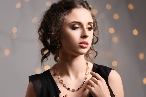 Jonge vrouw met mooie sieraden tegen intreepupil lichten - Foto, afbeelding