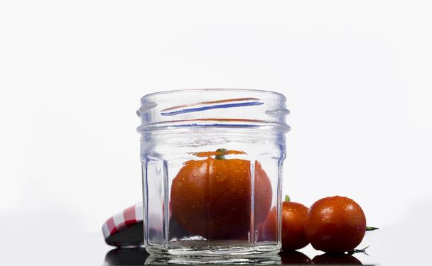 cherry tomaten op donkere achtergrond en jar voor saus. - Foto, afbeelding
