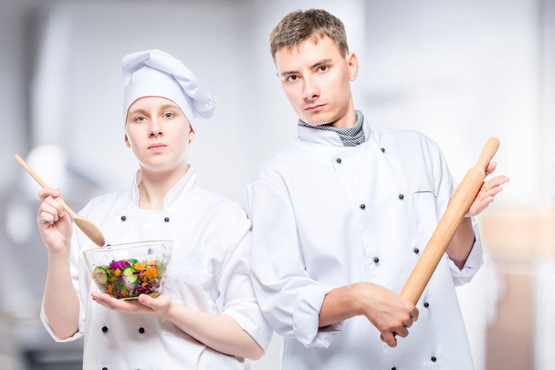 pareja profesional cocina con ensalada y rodillo sobre un fondo de cocinas comerciales - Foto, imagen