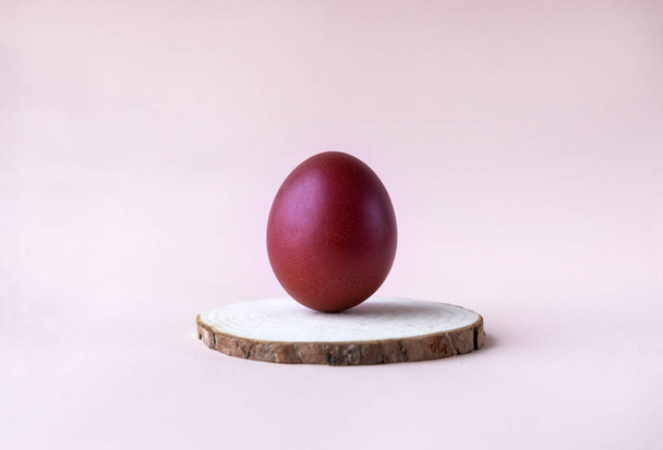 1 maroon Easter eggs on a wooden cut on beige background - Valokuva, kuva