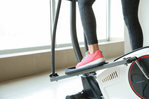 Sporty young woman using modern machine in gym - Foto, Imagen