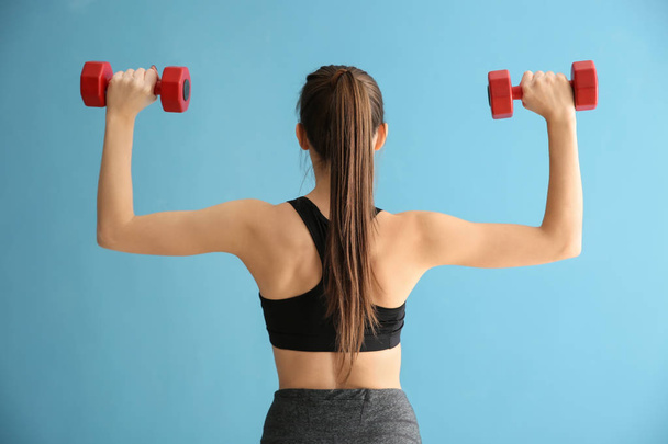 Sporty young woman with dumbbells on color background - Zdjęcie, obraz