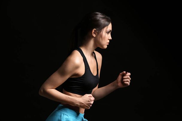 Sporty female runner on dark background - Φωτογραφία, εικόνα