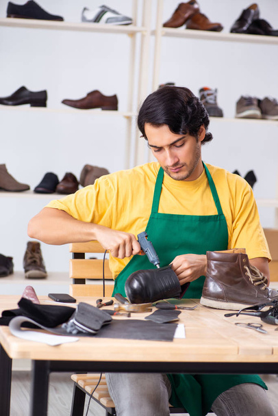Young man repairing shoes in workshop  - Foto, Bild