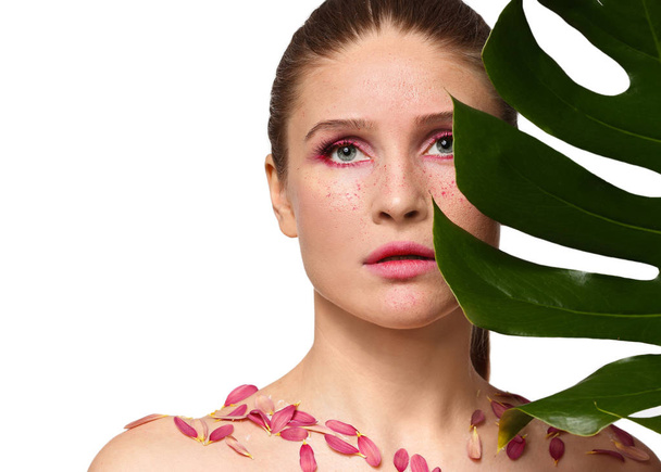 Beautiful woman with creative makeup and tropical leaf on white background - Φωτογραφία, εικόνα