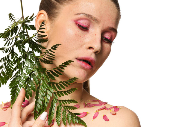 Mooie vrouw met creatieve make-up en tropische leaf op witte achtergrond - Foto, afbeelding