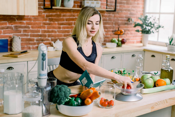 Young Woman weighs cherry tomatoes while Cooking salad in the kitchen. Healthy Food - Vegetable Salad. Diet. Dieting Concept. Healthy Lifestyle. Cooking At Home. Prepare Food - Foto, imagen