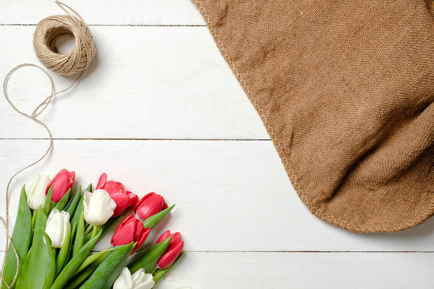 Bouquet of tulips flowers, blank picture frame, twine, burlap on white wooden table. Vintage greeting card for womans day, mothers day, birthday, easter. Rustic background, flat lay, above view. - Foto, afbeelding