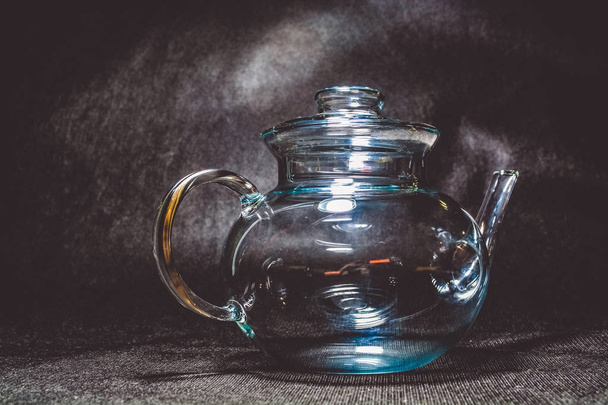 Transparent glass teapot for tea on a black monophonic background. Beautiful ware. - 写真・画像