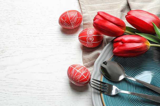 Festive Easter table setting with flowers on wooden background, top view. Space for text - Valokuva, kuva